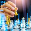 Chess game on chess board behind business man background. Business concept to present financial information and marketing strategy analysis. Investment target in global economy and digital commercial.