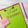 Word writing text Staff Training. Business photo showcasing A program that helps employees to learn specific knowledge Metal clipboard paper sheets marker sticky notes pad wooden background