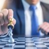 Close up hand of businessman playing chess and win in board game, strategy and planning business concept